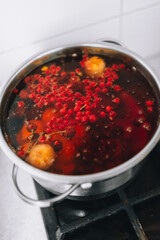 Cooking a delicious compote of apricot, apples, cherries, raspberries. Fresh fruits are boiled in boiling water in a metal pan on the stove. Photography, concept.