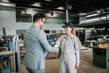  Young feYoung female worker handshake with handsome businessman at the factory workshop.male worker handshake with handsome businessman.