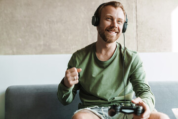 Photo of laughing man playing video game while making winner gesture