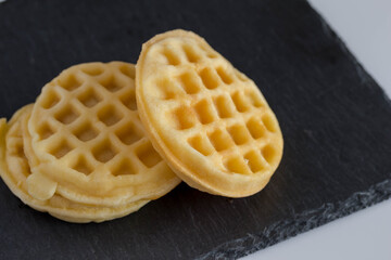 Round small waffles on black slate background waffles with copy space