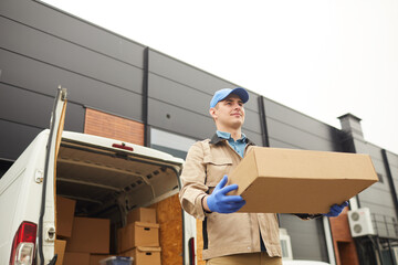 Young man in uniform carrying big cardboard box he working in cargo delivery