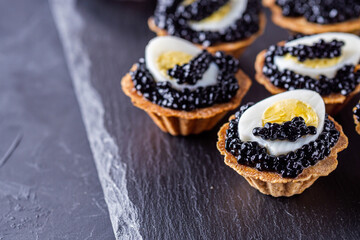 delicious snack tartlets on dark stone background