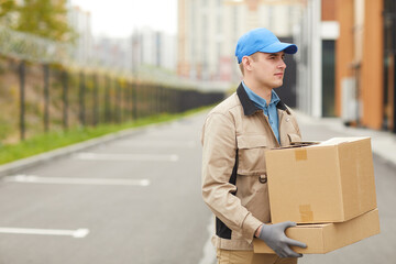 Young courier in uniform carrying boxes outdoors he delivering parcels