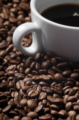 Cup of coffee drink sitting on a bed of roasted coffee beans background. Close up of a brown surface texture of aroma black caffeine drink ingredient for coffee beverage.
