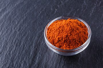 aromatic spicy chilli powder on a dark stone background