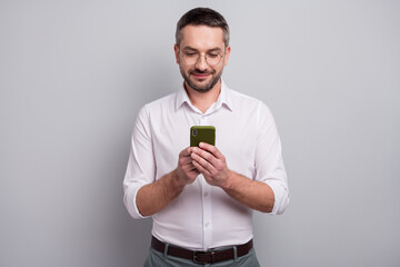 Portrait of his he nice attractive cheery focused mature man holding in hands cell chatting sending sms like follow subscribe isolated over light gray pastel color background