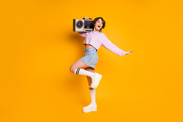 Fototapeta na wymiar Full length body size view of her she nice attractive lovely charming slender cheerful funny girl carrying boombox having fun dancing isolated on bright vivid shine vibrant yellow color background