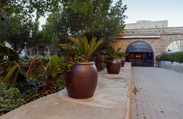 Large cadds with palm trees growing in them stand in the courtyard of the hotel King David in the light of the rays of the setting sun in Jerusalem, Israel
