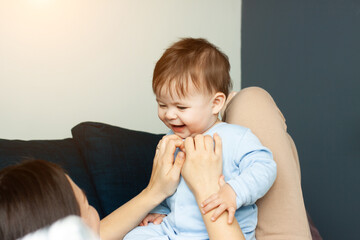 Fototapeta premium Mother plays of her baby. The baby is laughing. The concept of communication between parents and children, motherhood, the formation of affection.