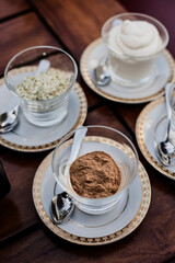 Overhead view of cinnamon powder, cocoa powder and cream in bowls on wooden table