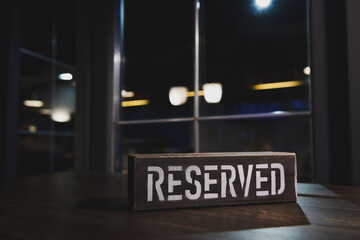 Vintage metal reserved table sign. Table reserve in restaurant. All tables are reserved. Dark bar. Copy space.