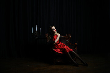 beautiful girl in a red dress posing in a chair on a black background