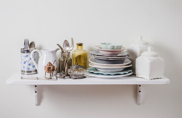 Buy old vintage romantic tableware in secondhand store concept. Pile of valuable old tableware on store shelf.