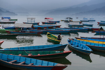 Fisherman surounded by small boats in Nepali lake
