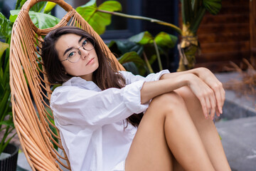 lovely Asian girl sitting in a rattan chair in the yard
