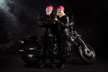 Obraz na płótnie Canvas Full length photo of aged bikers grey hair man lady couple drive vintage chopper traveling together feel young rock moto festival wear rocker leather outfit isolated black color background