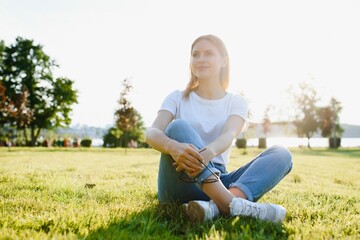 Fototapeta premium beautiful woman resting in the park on the grass in summer