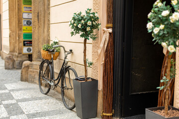 Old Europe style, a bicycle with a basket with fresh flowers is parked near the entrance to the house