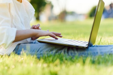 little girl play computer on green grass
