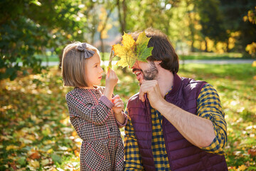 Obraz premium Father and daughter picking autumnal leafs