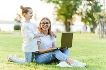 Mom and Daughter with laptop resting on meadow