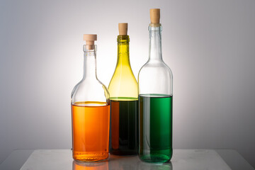 three bottles with alcohol of various colors on a gray background