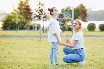 Fototapeta premium Mother and daughter having fun in the park. Happy family concept. Beauty nature scene with family outdoor lifestyle. Happy family resting together. Happiness and harmony in family life.
