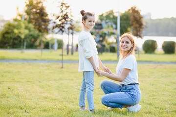 Fototapeta premium Mother and daughter having fun in the park. Happy family concept. Beauty nature scene with family outdoor lifestyle. Happy family resting together. Happiness and harmony in family life.
