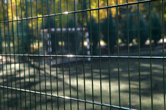 Blurred image of a sports field closed to the public. Lattice fencing at the stadium. Close-up, cropped shot, horizontal. Concept of quarantine and sports.