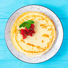 Pancakes with caramelized apples, raspberries, strawberries and red currants. Brunch with green tea and crepes.