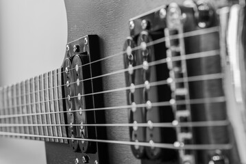 Fotografia czarno-biala gitary elektrycznej. Mostek metalowy w gitarze. Przetworniki muzyczne. Struny metalowe.