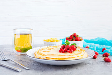 Pancakes with caramelized apples, raspberries, strawberries and red currants. Brunch with green tea and crepes.
