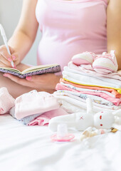 A pregnant woman is writing a list. Selective focus.