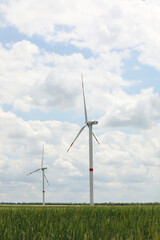 Fototapeta premium Modern wind turbines in field on cloudy day. Alternative energy source