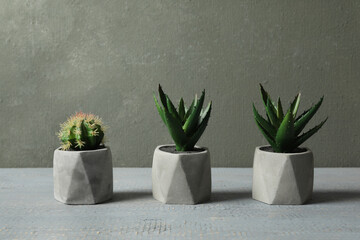 Artificial plants in ceramic flower pots on grey wooden table