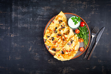 Delicious pancakes with mushrooms, ham and cheese, arugula, tomatoes and sour cream on a wooden background