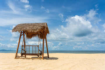Wooden swing under a thatched roof on a sandy tropical beach near sea on island of Phu Quoc, Vietnam. Travel and nature concept
