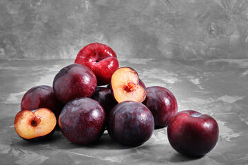 Obraz premium Ripe blue plums lie on a concrete stone background. Natural fruit background with place for text. Copy space. Autumn harvest background.