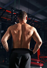 Fototapeta na wymiar Strong masculine man athlete doing standing in dark fitness club background. Closeup portrait.