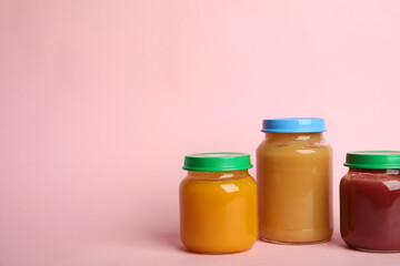 Jars with healthy baby food on pink background, space for text