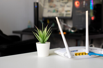 Close up of a wireless router on table at home with desktop computer background