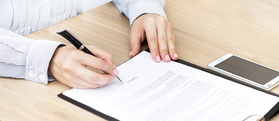 Girl sits at a table and signs a contract. Business