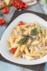 Penne pasta in creamy sauce with chicken, tomatoes decorated with parsley