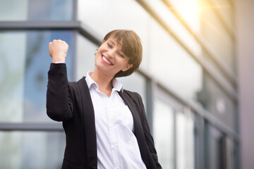 an expressive and happy businesswoman outside