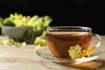 Cup of tea and linden blossom on wooden table. Space for text