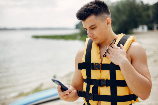 Handsome Man With A Sup. Surfer In A Yellow Vest. Man Use The Phone