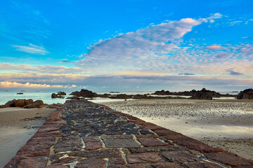 Image of the stone pier at Green Island with calm sea, beach, blue sky with couds. Jersey, Channel Islands