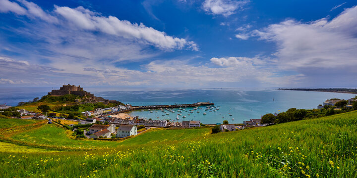 Image of Gorey Castle with Harbour, Grouville Bay calm sea and blue sky and clouds. Jersey, Channel Islands.