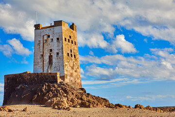 Fototapeta na wymiar Image of Seymour Tower at low tide with stones, cloudy sky and sunshine.