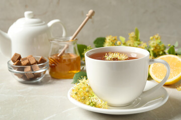 Cup of tea with linden blossom on light grey marble table